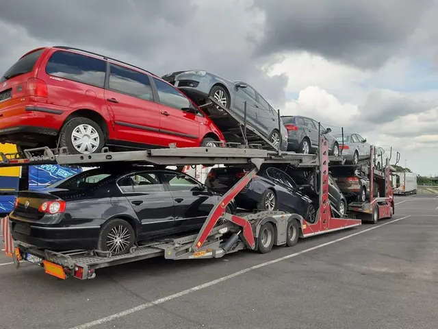 Platformă auto Romfour încărcată cu autoturisme, printre care un hatchback roșu