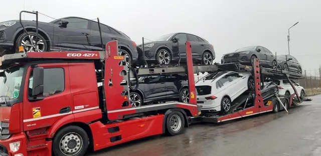 Cap tractor roșu Romfour cu platforma complet încărcată, pe asfalt umed