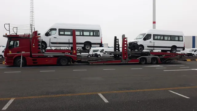 Platformă Romfour transportând microbuze Renault Master albe