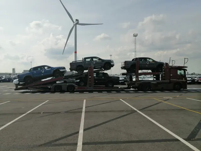 Transport auto pe platformă Romfour, lângă o turbină eoliană